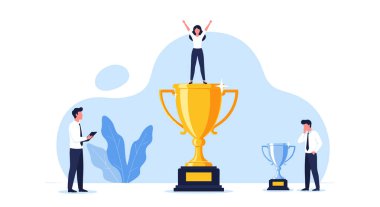 Başarılı bir kadın zaferini kutlarken yanında küçük gümüş ödüller tutan meslektaşlarıyla dev bir altın kupanın üzerinde duruyor..