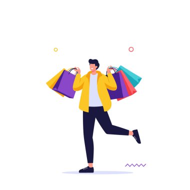 Küçük dekoratif noktalı beyaz bir arka plana karşı neşeyle poz verirken elinde birden fazla renkli alışveriş torbaları tutan mutlu genç adam..