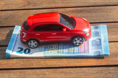 Bir yığın banknotun üzerinde kırmızı oyuncak araba.
