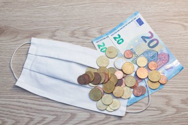 Beyaz kumaş maskesi, euro banknotları ve madeni paralar