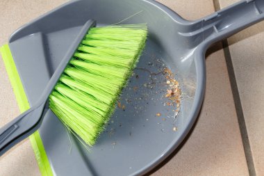 Bir evin zemininde tozla fırça ve faraş.