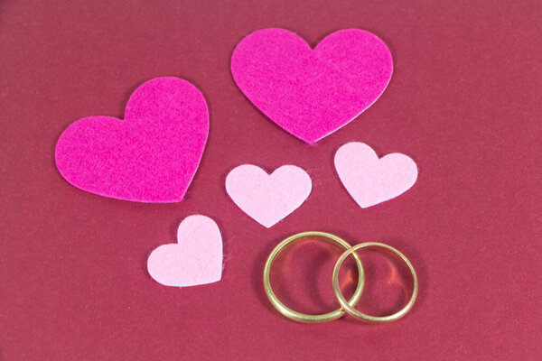 Два обручальных кольца и розовые сердечки на день Святого Валентина
