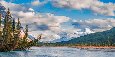 Majestic Mountain River Scene, Jasper Ulusal Parkı 'ndaki Edith Dağı yakınlarındaki çarpıcı manzarayı gözler önüne seriyor. Nehir, dağlık arazide kendi yolunu açarken güçlü bir şekilde akar..