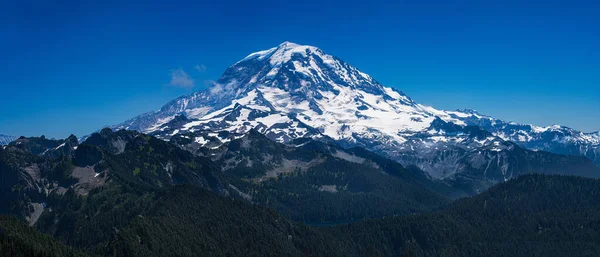 Rainier Dağı 'nın karlı zirvesi Washington' daki Rainier Dağı Ulusal Parkı 'nın manzarasına hakim. 1899 'da kurulan park bu ikonik dağın görkemli yeşil manzarasını korur..