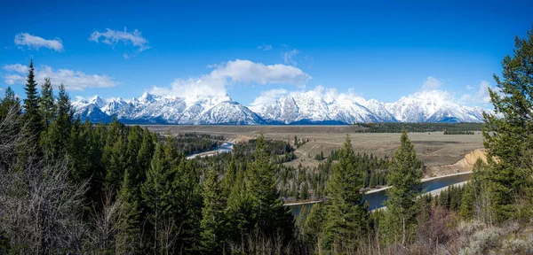 Yılan Nehri Grand Teton Ulusal Parkı 'na doğru eserken nehir içinden akıyor. Bulutlu Grand Teton Dağları doğal manzaraya çarpıcı bir zemin sağlar..