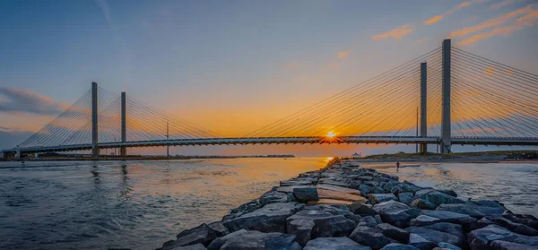 Delaware 'deki Indian River Inlet' in üzerinde nefes kesici bir gün batımı görüldü. Delaware Seashore State Park 'ın Indian River Cut' ı içinde göze çarpan bir özellik. Altın güneş ışınları köprü yapısını dramatik bir şekilde delip geçti.