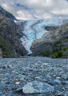 Buzul 'dan çıkış engebeli dağların arasından bir yol kazıyor, buzlu mavi yüzeyi koyu morinalarla işaretlenmiş..