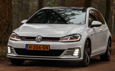 Gündüz vakti güz ormanlarından geçen modern bir araba. 