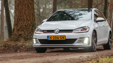 Gündüz vakti güz ormanlarından geçen modern bir araba. 