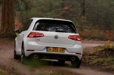 Gündüz vakti güz ormanlarından geçen modern bir araba. 