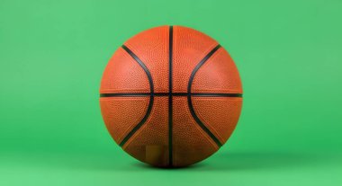 A close-up studio shot of a standard orange basketball, isolated on a solid green backdrop.