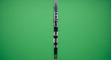 A medical syringe filled with clear liquid is shown vertically against a vibrant green backdrop, highlighting its components and contents.