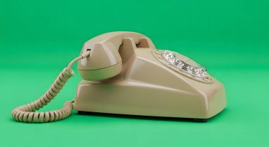 A classic beige rotary dial telephone with a coiled cord rests on a solid green backdrop, evoking a sense of nostalgia and retro technology.