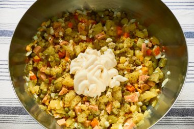 Olivier salatasının tepeden tırnağa metal bir kasede, sebze, sosis, yumurta ve kremalı mayonezle karıştırılmış hali. Noel ya da Yeni Yıl için mükemmel bir hazırlık..