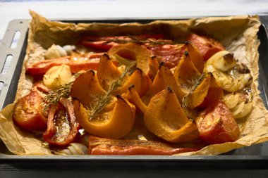 Kabak, biber, biberiye, soğan ve parşömen kağıdında kızartılmış sarımsak manzarası. Sıcak sonbahar mutfak sahnesi, mevsimlik yemek ve hasat yemekleri için mükemmel..