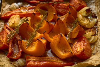 Kızarmış balkabağı, biber, soğan, sarımsak ve parşömen kağıdına biberiye yakın plan. Sıcak sonbahar mutfak sahnesi, mevsimlik yemek ve hasat yemekleri için mükemmel..