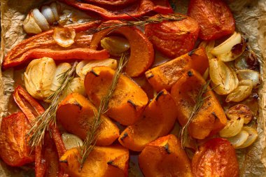 Kızarmış balkabağı, biber, soğan, sarımsak ve parşömen kağıdında biberiye. Sıcak sonbahar mutfak sahnesi, mevsimlik yemek ve hasat yemekleri için mükemmel..