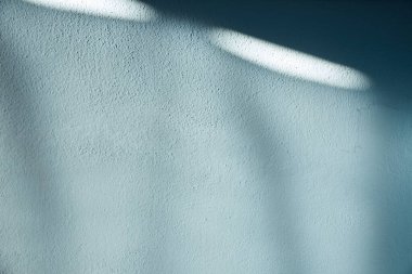 Yumuşak mavi bir duvar, ince dokuları ve doğal gölgeleri ile soyut, yüzeyde uzatılmış şekiller yaratıyor. Grafik tasarımı, modern düzenler, ürün sunumları ve sakin görsel kompozisyonlar için ideal.