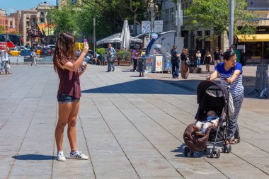BARCELONA, SPAIN - 15 Mayıs 2017: Placa Nova caddesinde (Barselona Katedrali yakınlarında) duran ve telefonla fotoğraf çeken bilinmeyen genç kadın.