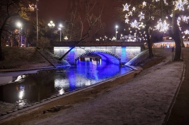 Riga 'daki Bastion Hill şehir parkında (Letonya) Alexander Köprüsü' nün gece manzarası. Köprü 1858-1859 yılları arasında inşa edildi ve 1902 yılında genişletildi..