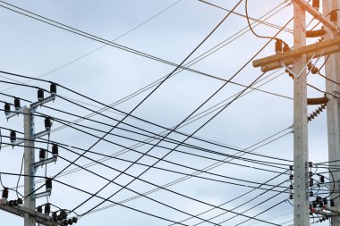 Bu görüntü, şehir karmaşıklığını ve yaşlanan altyapıyı sembolize eden somut bir elektrik direğini aşırı yükleyen kaotik elektrik kabloları ve iletişim kablolarını yakalıyor..