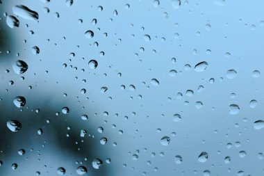 Sayısız su damlacıklarının makro, detaylı bir görüntüsü ve serin mavi cam bir yüzey üzerinde çizgiler, nemli hava arkaplanı için güzel, soyut bir doku yaratıyor..