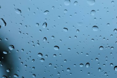 Sayısız su damlacıklarının makro, detaylı bir görüntüsü ve serin mavi cam bir yüzey üzerinde çizgiler, nemli hava arkaplanı için güzel, soyut bir doku yaratıyor..