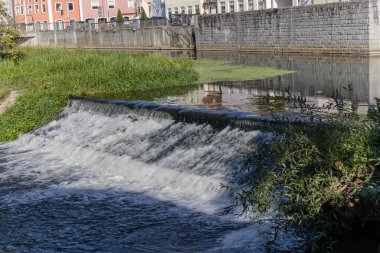 Küçük bir barajın manzarası çağlayan su ve nazik nehir yansımalarıyla geniş bir vadi oluşturuyor. Manzaralar, çevre kavramları ve yenilenebilir enerji illüstrasyonu için uygundur.