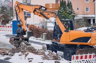 Kışın karlı bir yolda donmuş toprak kıran kazıcı kovasının detaylı görüntüsü..
