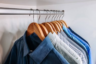 Minimalist bir gardırop. İçi boş ahşap askılarla dolu. Metal bir çubuğa yerleştirilmiş..