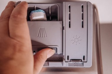 Sabun kutusuna yerleştirilmiş bulaşık deterjanı tabletinin yakın çekimi. Temizlik ürünü ve ev aletleri detay kavramı.