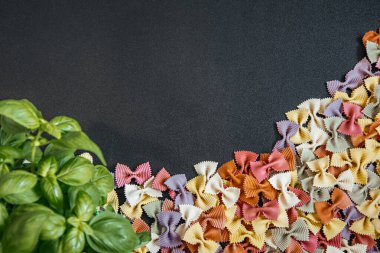 Renkli makarna ile arka planda en az besin değeri koyu yüzeyde sıralanmış. Tarifler, menüler, afişler ve gıda markaları için kopyalama alanı olan temiz ve modern kompozisyon.