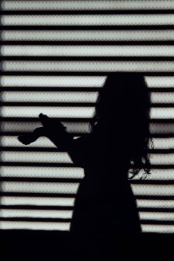 Dramatik çizgili pencere gölgesinde el hareketleriyle etkileyici kız silueti. Özgürlük ve yaratıcılık kavramı.