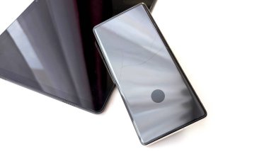 Beyaz arka planda görünen kırık cam ekranlı modern akıllı telefon. Cihaz hasarı, tamir hizmeti, sigorta, kaza, teknoloji arızası veya yedek elektronik konsepti