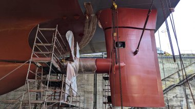 Geminin kıç tarafını pervane ve dümenle kapatın. Bakım altında, iskele ve koruyucu kaplama endüstriyel gemi onarımı sırasında kuru rıhtımda görülebilir.