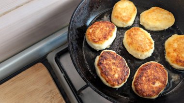 Süzme peynirden yapılmış taze şurup fırının üstünde tavada kızartılıyor. Sıcak bir mutfak ortamında geleneksel bir ev yapımı kahvaltı hazırlarken altın kabuk oluşuyor.