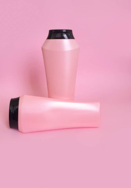 Renkli pembe arka planda bir şişe şampuan ve merhem.