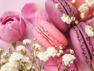 çok renkli badem kurabiyesi, renkli bir arka planda gül çiçeği.