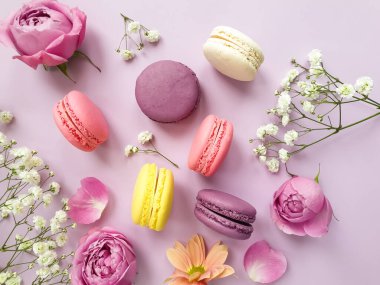 çok renkli badem kurabiyesi, renkli bir arka planda gül çiçeği.