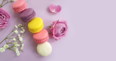 çok renkli badem kurabiyesi, renkli bir arka planda gül çiçeği.