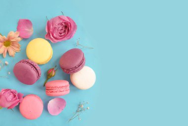 çok renkli badem kurabiyesi, renkli bir arka planda gül çiçeği.