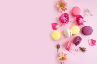 çok renkli badem kurabiyesi, renkli bir arka planda gül çiçeği.