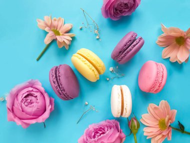 çok renkli badem kurabiyesi, renkli bir arka planda gül çiçeği.