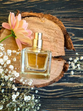 Ahşap bir arka planda şişe parfümü çiçeği.