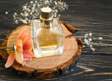 Ahşap bir arka planda şişe parfümü çiçeği.