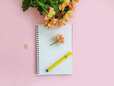 Renkli bir arkaplanda defter, kalem, çiçekler