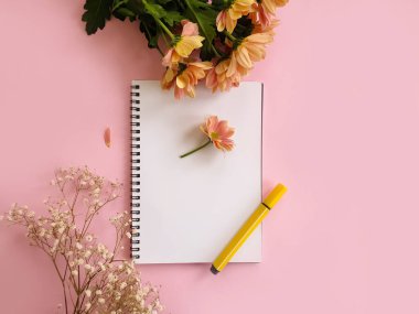 Renkli bir arkaplanda defter, kalem, çiçekler