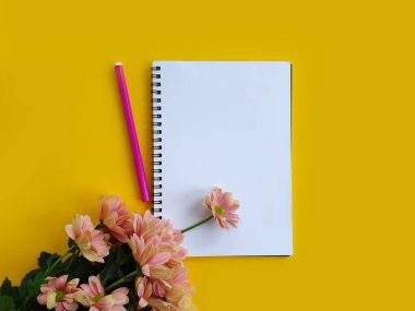 Renkli bir arkaplanda defter, kalem, çiçekler