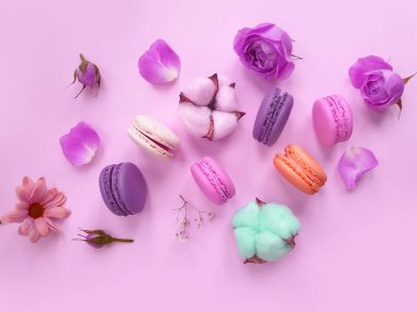 çok renkli badem kurabiyesi, renkli bir arka planda gül çiçeği.