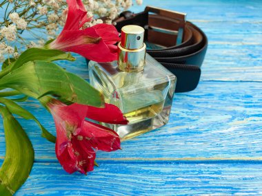 Parfüm şişesi, tahta arka planda kemer.